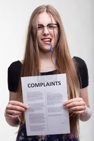 Focused professional analyzes complaints with a critical eye, pen in mouth
