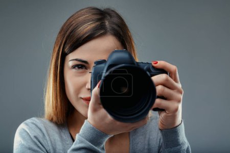 Mujer con cámara muestra una mezcla de concentración y arte, ojo afilado detrás de la lente