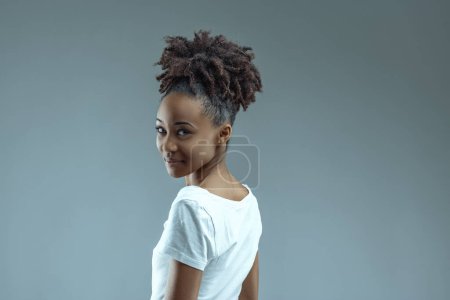 With a twist, young Black woman glances back, expression playful and inviting