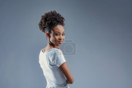 Half-turned, she offers a bright, cheeky smile, her Afro hairstyle prominent