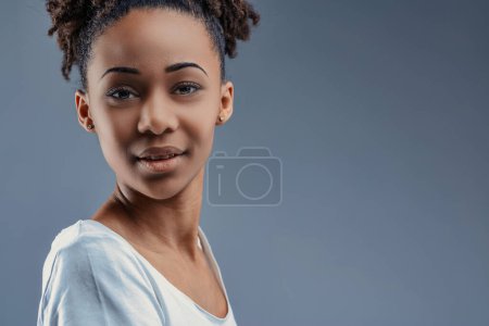 Graceful in her semi-turned stance, a young woman of African descent smiles
