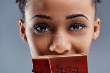Les yeux intenses d'une jeune femme regardent au-dessus d'un journal rouge décoratif, faisant allusion à des histoires inracontées