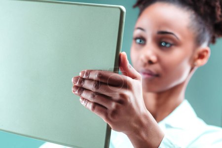 Con atención meticulosa, una mujer con una bata blanca estudia los detalles en la pantalla de su tableta