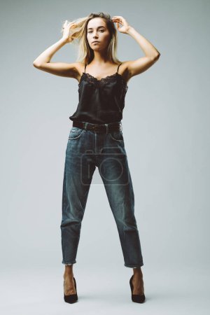 Stilvoll in Spitze und Jeans gekleidet, verkörpert sie einen unbeschwerten Geist, ihre Pose suggeriert einen Tanz in der Mitte der Bewegung