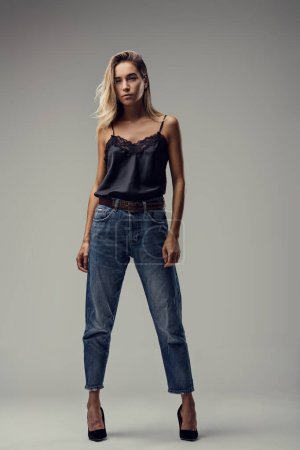 Eleganz in Schlichtheit, das Bild zeigt sie in einem schwarzen Top aus Spitze, Jeans und High Heels, die lässige Anmut verströmen