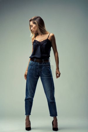 Ganzkörperporträt einer jungen Frau, die lässige Jeans mit der zarten Weiblichkeit eines schwarzen Spitzenoberteils kombiniert