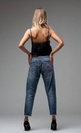 casual roll-up of her jeans pairs with high heels, contrasting with the fluid elegance of her silk top