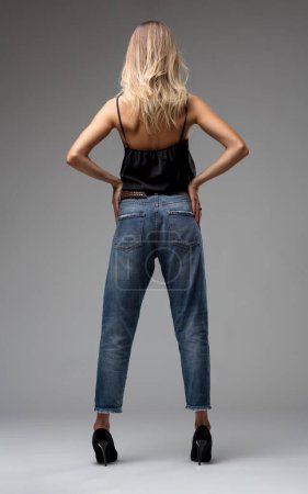 Mit dem Rücken zur Wand strahlt sie eine nonchalante Eleganz aus, ihre Jeans und Absätze verkörpern lässige Eleganz