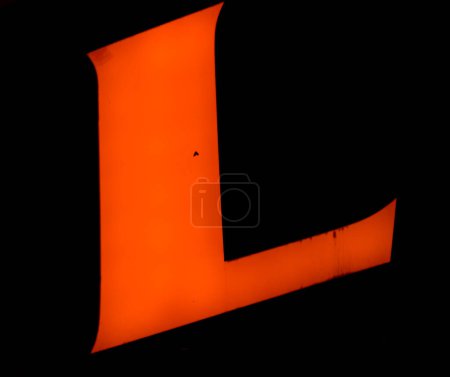 The letter 'L' shines brightly in orange, its bold angle cutting through the blackness of the night