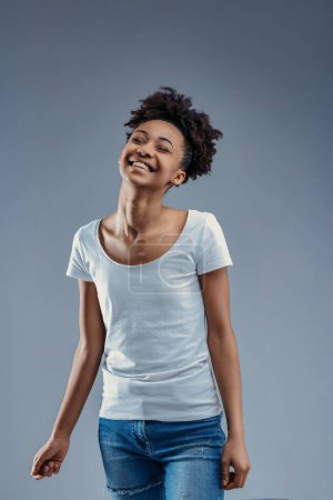 Delightful young woman enjoys a light moment, her afro and casual style epitomizing relaxed joy