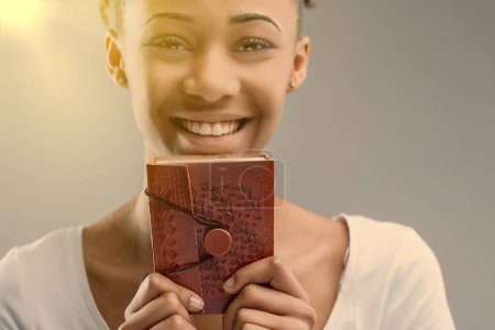 Blick in die gefühlvollen Augen einer jungen Frau hinter einem roten, geprägten Ledertagebuch