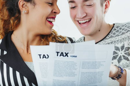 Man and woman share a light-hearted moment while reviewing tax documents, seemingly unbothered by the financial chore