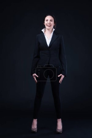 Confident young woman in a black business suit smiles broadly, exuding professionalism and charm