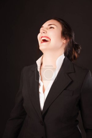 Mujer joven exuberante en traje de negocios disfruta de un momento de luz, su risa resonando profesionalismo y alegría