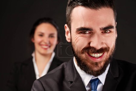 Two young professionals laugh deviously after securing a business deal in their favor, displaying cunning smiles