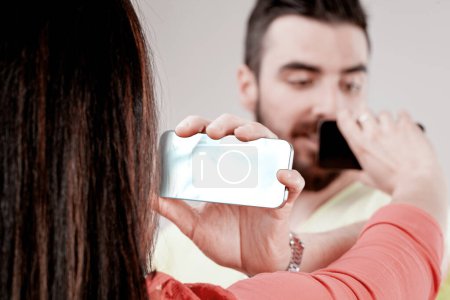 Sichtlich aufgeregt zeigen Mann und Frau einander ihre Smartphone-Bildschirme und verwenden dabei Visuals als Ersatz für verbale Kommunikation.