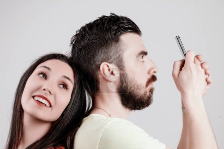 Mujer joven mira con anhelo a un hombre que se centra en su teléfono inteligente, que desea iniciar una conversación que es ajeno a