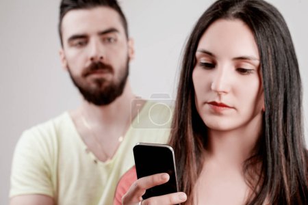 man's jealous vigilance through his smartphone conflicts with his partner's troubled look, hinting at deeper issues in their relationship