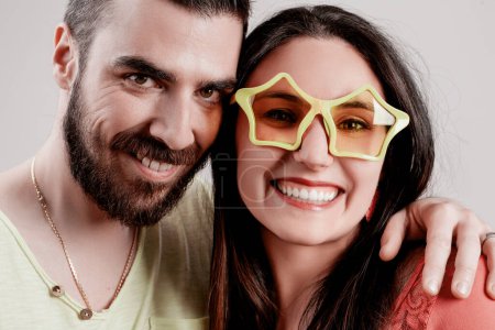 Bright, cheerful expressions dominate this image of a couple; the womans quirky star-shaped glasses add a fun, lighthearted touch to their bond 