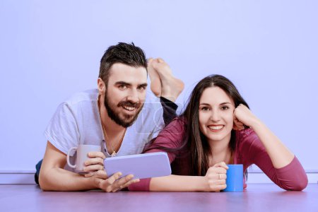 Couple profite d'un moment de détente, partager des rires et du contenu numérique sur une tablette, leur joie et leur compagnie évidente