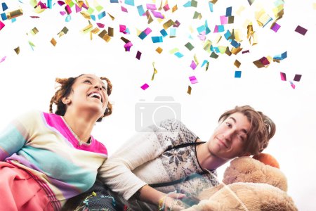 Playful scene with a young woman and man, each adorned in playful attire, engaging with a plush bear and balloons