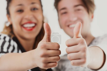 Playfully giving thumbs up, this young couple radiates happiness and approval, capturing a moment of shared joy