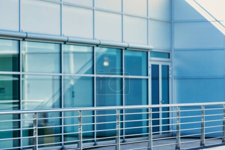 Moderne Architektur eines Bürogebäudes mit reflektierenden blauen Fenstern und einem stabilen Metallgeländer, das zeitgemäßes Design präsentiert