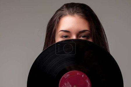 Radiant eyes full of joy peek out from behind a vinyl record, expressing sheer delight