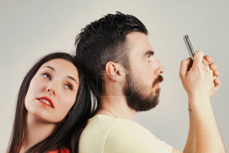 Mujer anhela conversación; hombre preocupado con su teléfono, brecha de comunicación palpable entre ellos