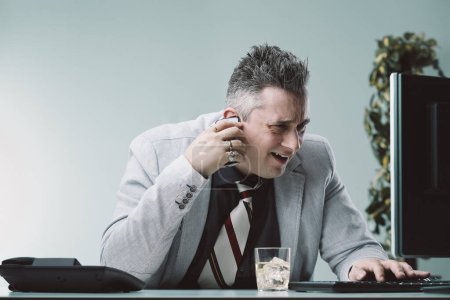 Businessman in a light grey suit looks frustrated and confused as he listens to explanations on the phone about his screen