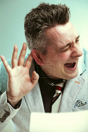 Homme en costume fait un geste indiquant qu'il ne peut pas entendre, symbolisant l'évitement dans une conversation potentiellement litigieuse