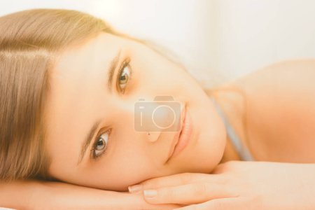 Portrait en gros plan d'une jeune femme allongée, le regard doux et accueillant, soulignant son comportement paisible