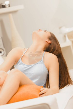 young woman's posture and closed eyes suggest a moment of personal reflection or meditation in a comfortable home setting