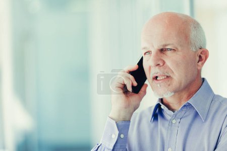 Geschäftsmann im blauen Hemd telefoniert vor einem Bürokomplex und zeigt Konzentration und Entschlossenheit