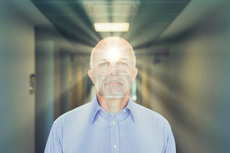 Elderly man glows from within, light casting forward from his presence in a corridor, exuding vitality and focus
