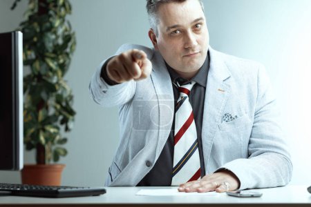 middle-aged man in a light suit and striped tie points directly at the viewer, his expression confident and assertive. He seems to be saying that you are the right person for the job
