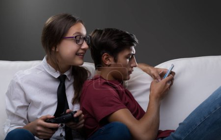 Dicht gedrängt blickt ein Mädchen auf den Handybildschirm eines Jungen über seiner Schulter. Der Junge, konzentriert auf sein Handy, scheint unglücklich über das aufdringliche Verhalten des Mädchens zu sein