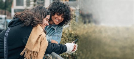 Téléchargez les photos : Jeune couple multiracial regardant le téléphone mobile dans la rue - en image libre de droit