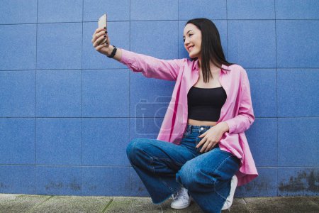 Foto de Chica urbana con teléfono móvil en la pared azul - Imagen libre de derechos