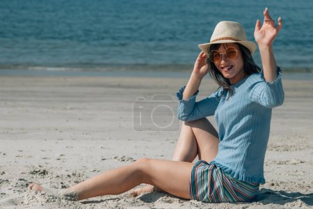 Téléchargez les photos : Heureuse jeune femme agitant la main sur la plage - en image libre de droit