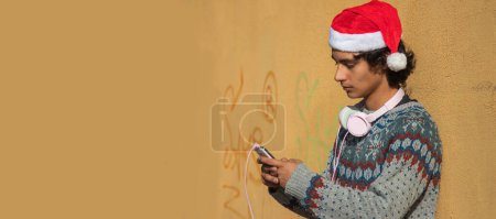 Foto de Joven con auriculares y teléfono móvil en la calle en Navidad - Imagen libre de derechos