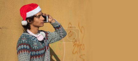 Foto de Joven con auriculares y teléfono móvil en la calle en Navidad - Imagen libre de derechos