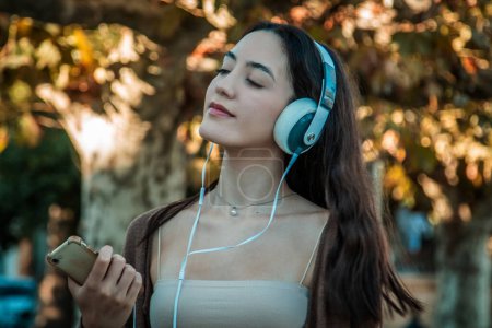 Photo for Young woman with headphones in autumn park - Royalty Free Image