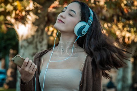 Photo for Young woman with headphones relaxed in autumnal background - Royalty Free Image