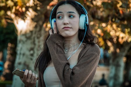 Photo for Young woman with headphones in autumn park - Royalty Free Image