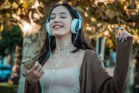Photo for Young woman with headphones dancing on autumn background - Royalty Free Image