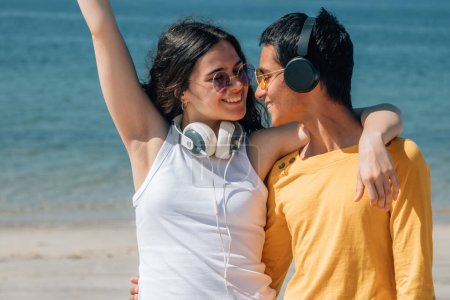 Foto de Pareja joven y relajada con auriculares disfrutando en la playa - Imagen libre de derechos