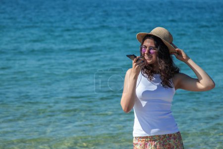 junge Frau am Strand und sendet eine Audiobotschaft mit dem Telefon