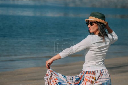 sonriente mujer joven en la playa en el estilo de verano moda tendencia traje despreocupado y feliz, sensación de libertad, estilo boho chic y gafas de sol