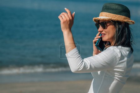 Téléchargez les photos : Jeune femme avec téléphone portable sur la plage et dire bonjour - en image libre de droit